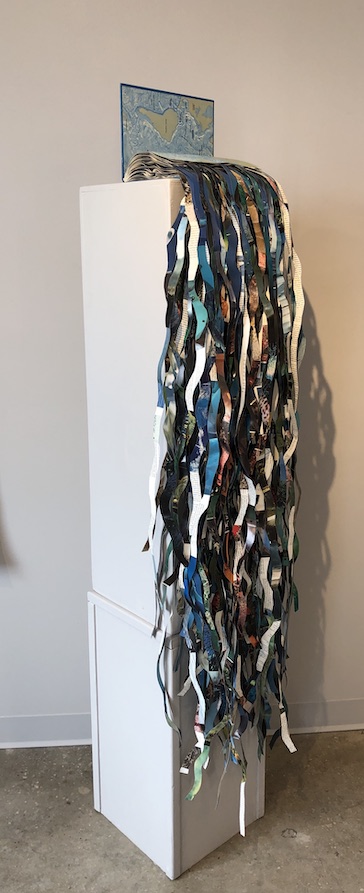 An artwork by Maggie Kerrigan that depicts ribbons of colored paper spilling out of a book.