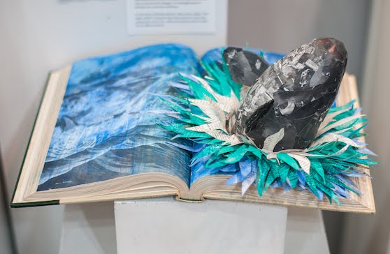 An artwork by Maggie Kerrigan that shows a whale breeching out of the open pages of an encyclopedia.