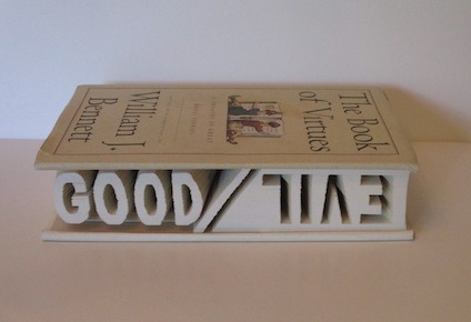 An artwork by Maggie Kerrigan made out of a book that has been hand-carved to show the words Good and Evil