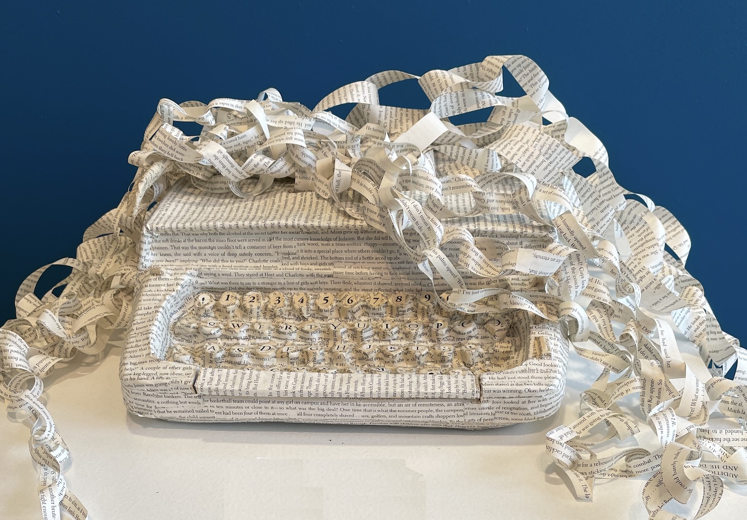 An artwork called The Infinity of Imagination by artist Maggie Kerrigan. It's a manual typewriter that has been cast in paper and has ribbons of book text flowing out of it.