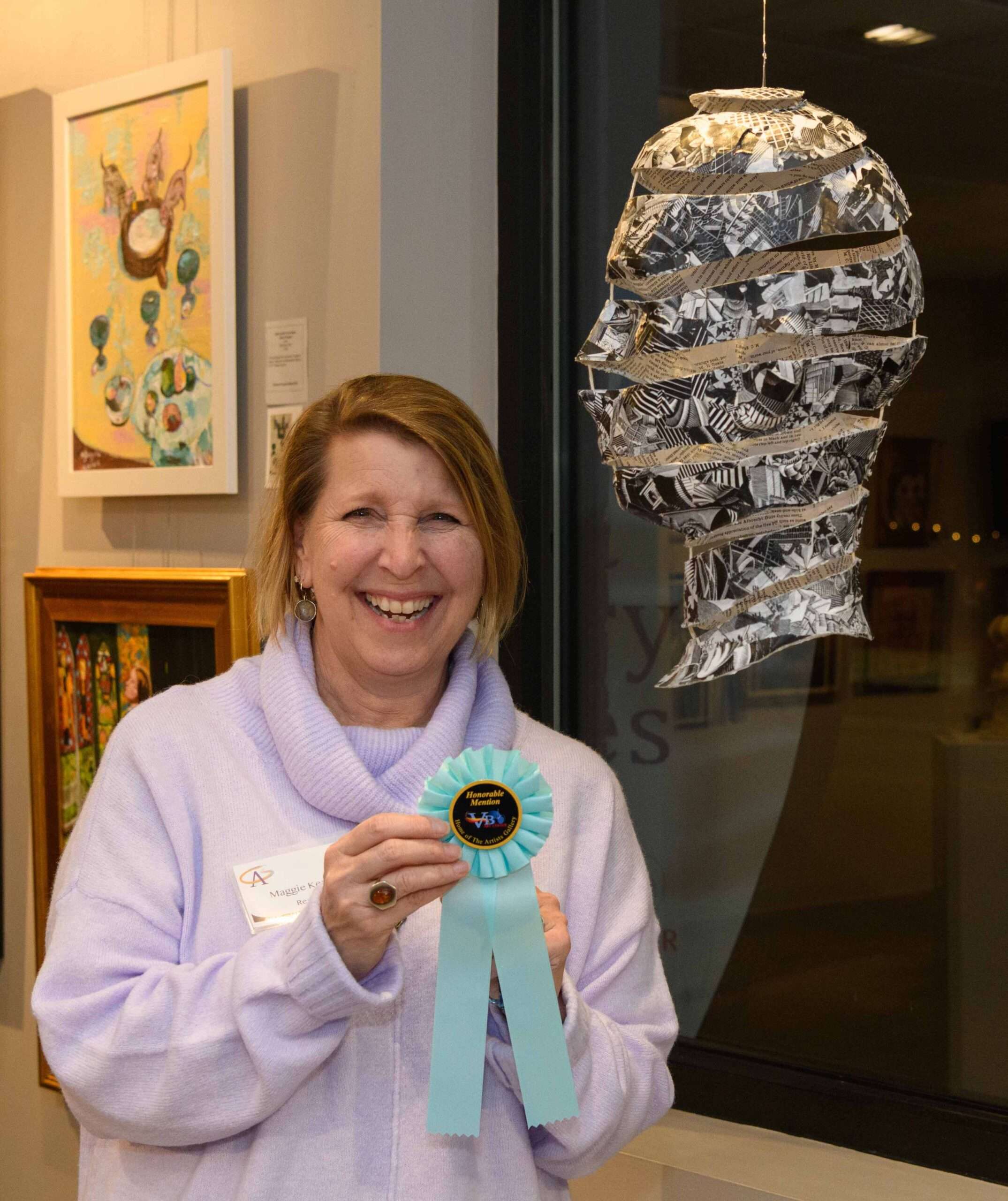 Maggie Kerrigan poses with her honorable mention award and her artwork, "The Escher Head"