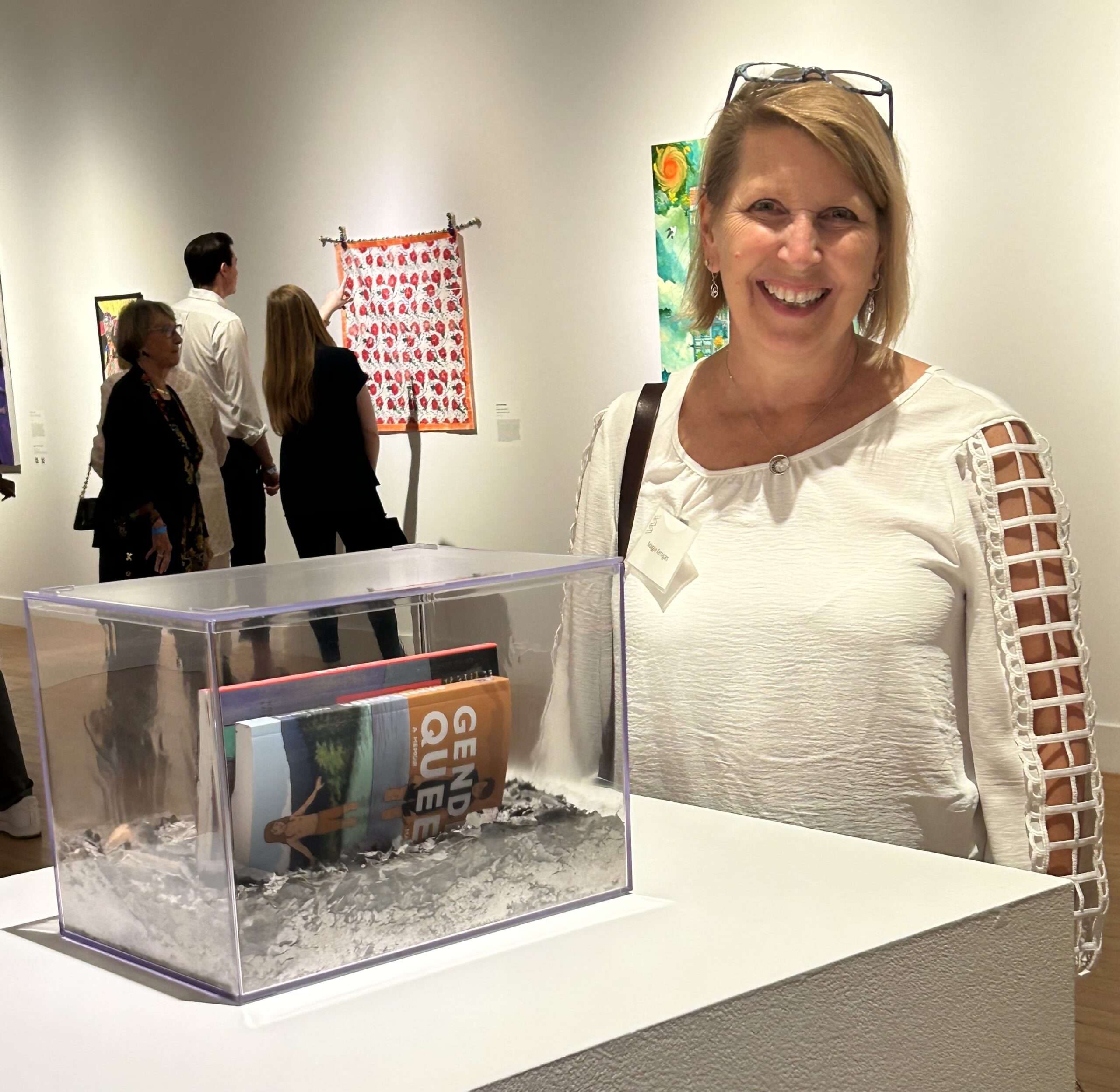 Artist Maggie Kerrigan poses with her artwork Rise from the Ashes, which consists of two "banned" books and the ashes of 7 burned books.
